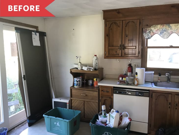 A messy kitchen with dark brown cabinets and scattered cleaning supplies