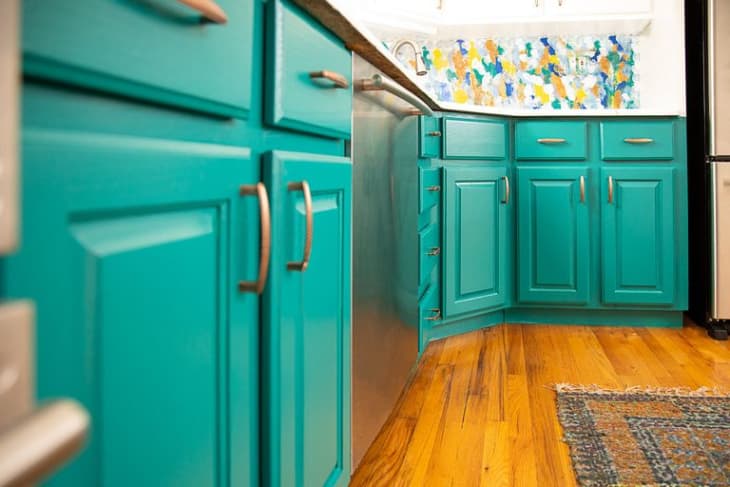 Kitchen with teal painted cabinets and a multicolored backsplash