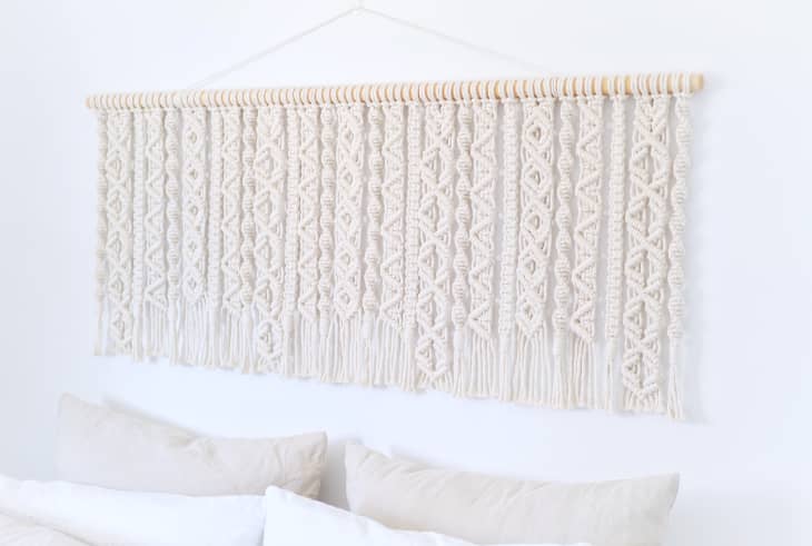 Cream-colored macrame wall hanging above bed