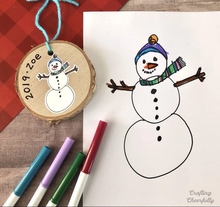 Snowman ornament, markers, and kid's drawing of snowman