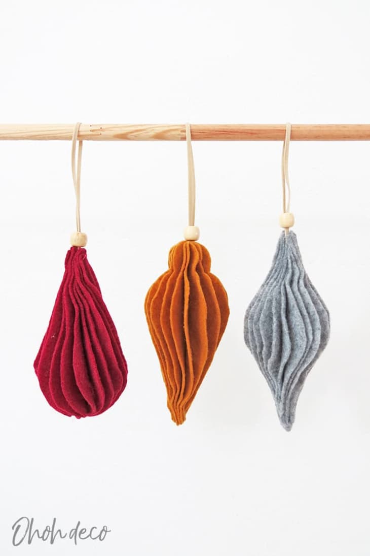 Red, orange, and gray felt ornaments hanging from rod
