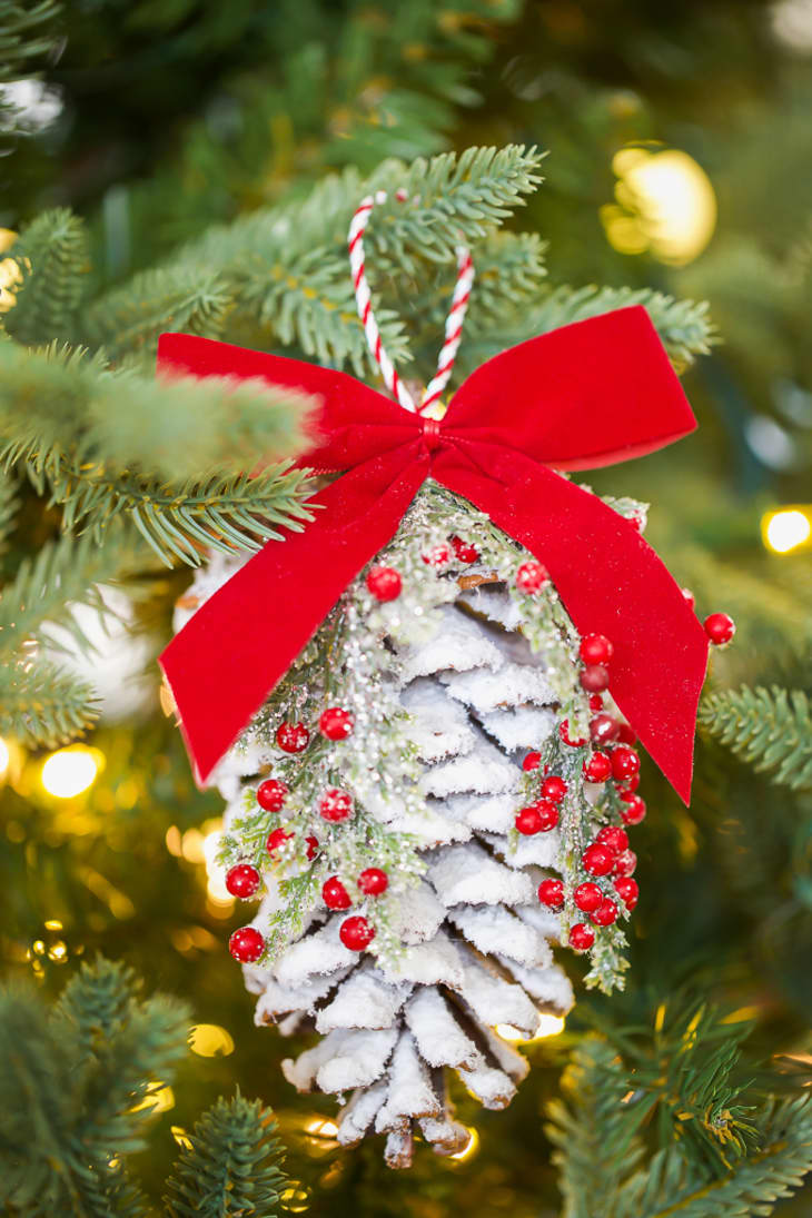 Pinecone ornament with red bow hanging in tree