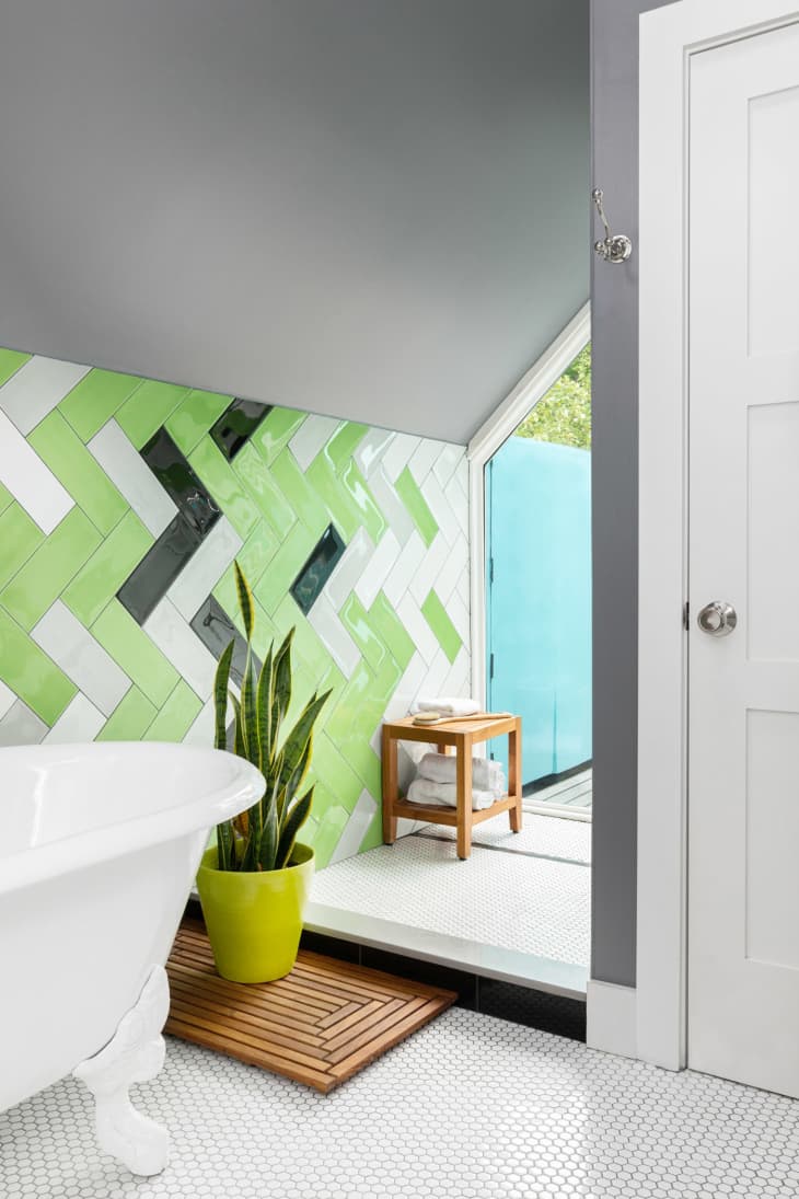 Bathroom with green tiled walls and plant in yellow pot