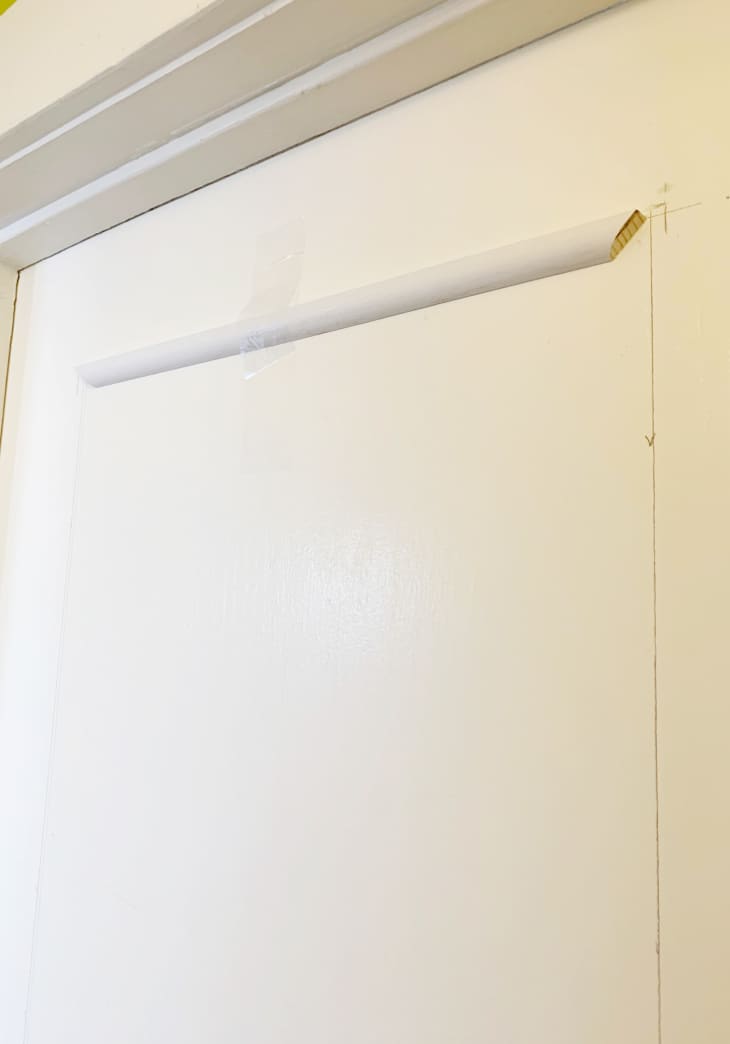 White door with pencil line marking where trim would go, and a cut piece of trim taped up