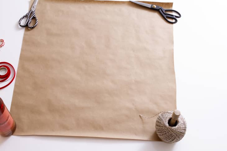 square of brown paper held down by twine and scissors