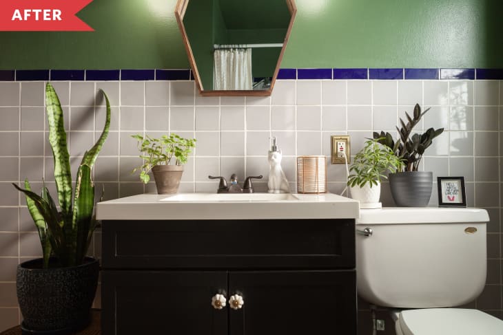 Bathroom with gray and blue tile, green walls, and hexagonal mirror