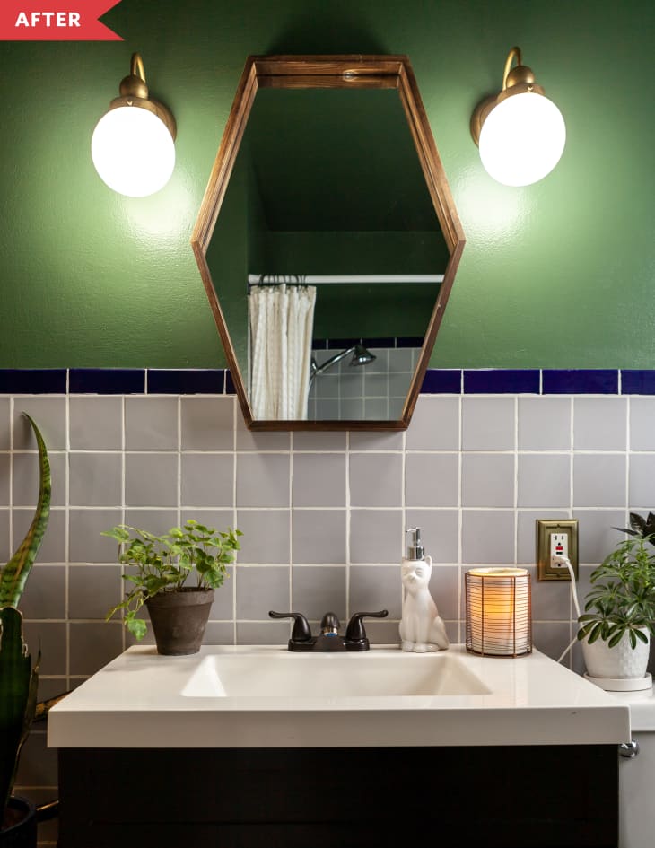 Bathroom with gray and blue tile, green walls, and hexagonal mirror