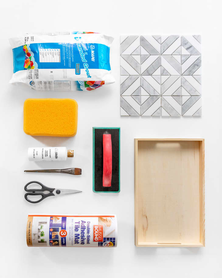 Materials including scissors, adhesive, wooden tray, and gray and white geometric tile