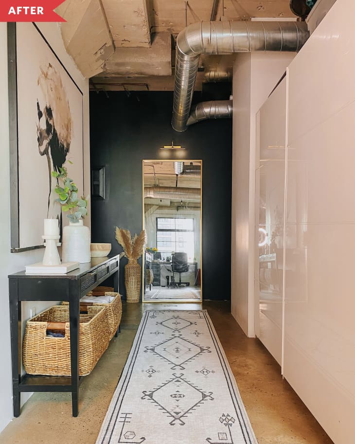 After: Entryway with white and black walls, a black console table, a white and black patterned rug, and a floor length mirror