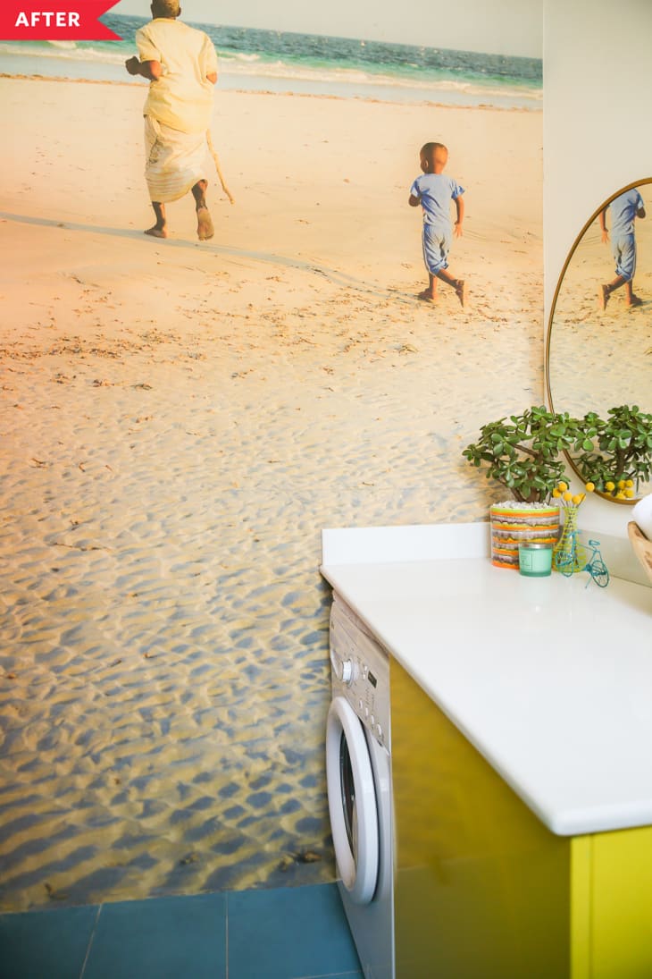 之后:浴室里有一个黄色的柜子，里面有洗衣机/烘干机，靠着墙上有两个人在海滩上的照片壁画