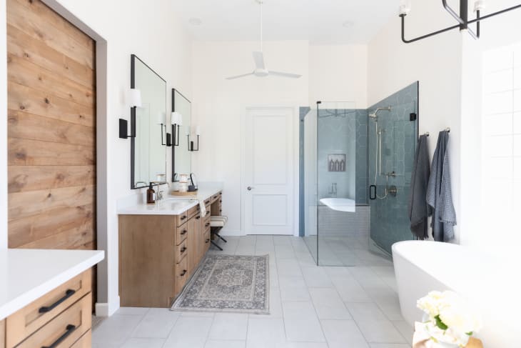 White bathroom with wide-door shower that features blue tile