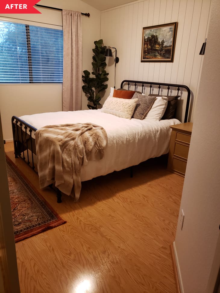 之后：卧室配有垂直的白色涂木镶板，农舍式的铁床框架，窗口上窗帘