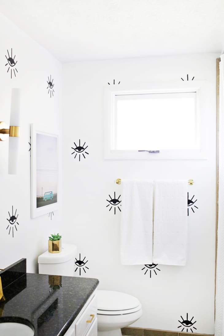 Bathroom with white walls and black eye patterns all over the walls
