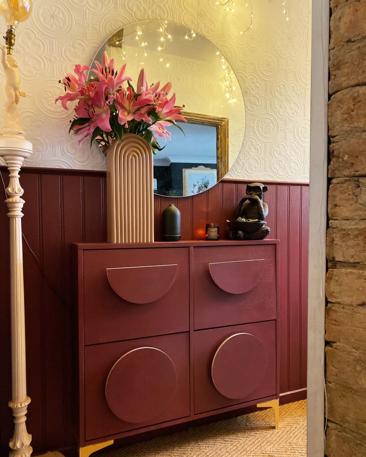 an entryway's narrow shoe cabinet painted maroon, to match wainscoting behind it.