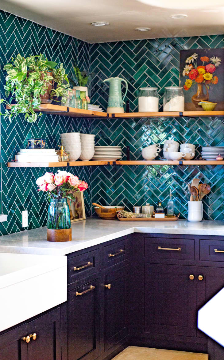 Kitchen with green tile backsplash in chevron pattern, open shelves, and a white stone countertop over purple painted cabinets