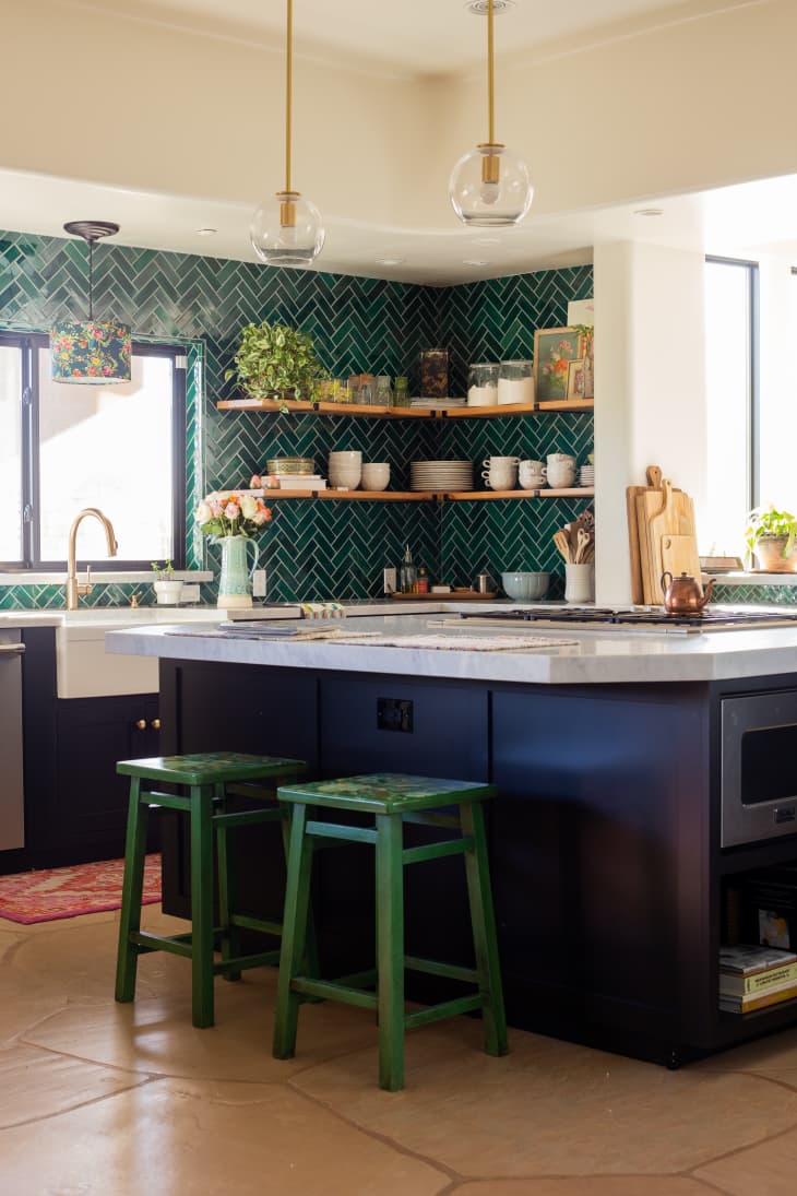 Kitchen with green tile backsplash in chevron pattern, and a large island with a marble countertop