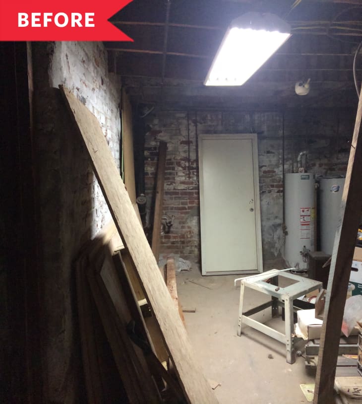 Before: Unfinished living room with exposed brick and water tanks, white door, and rectangular overhead light
