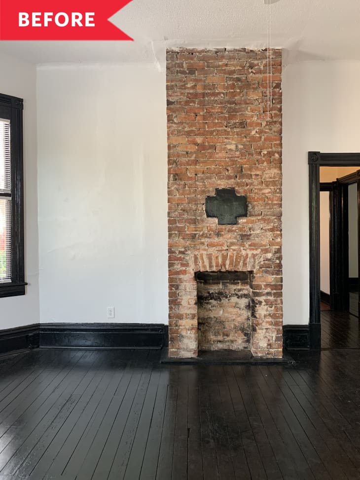 Before: Floor-to-ceiling brick fireplace in room with white walls and black floors and trim