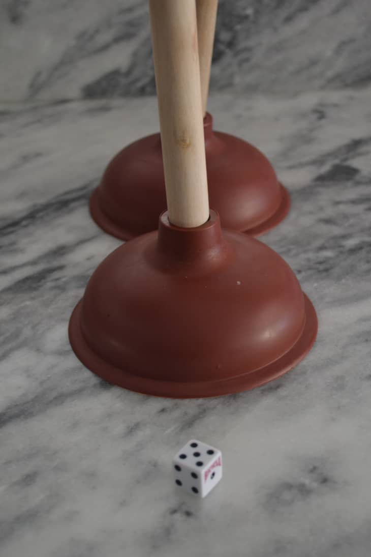 die with a number five facing up, next to two plungers