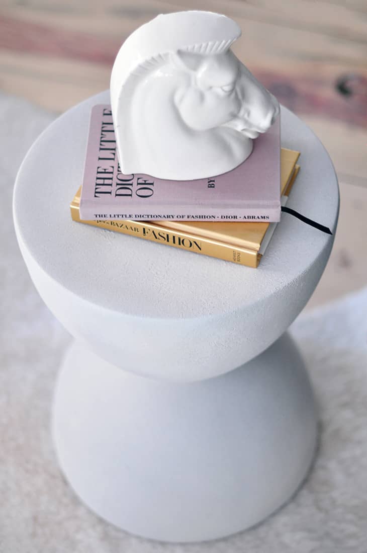 Faux stone accent table in a light gray tone, with books stacked on top