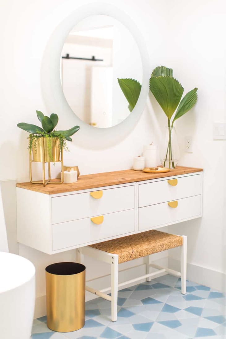 White floating dressing table with gold pulls and wood top, made from IKEA EKET cabinets.