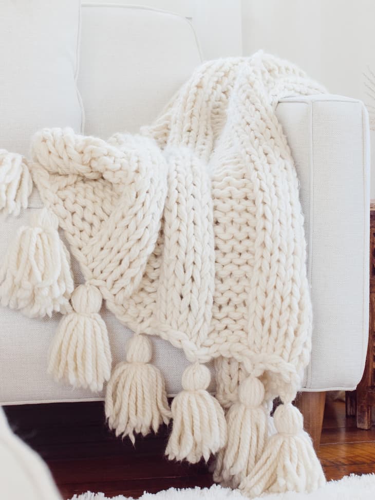 knit blanket in white with tassels on the edge.