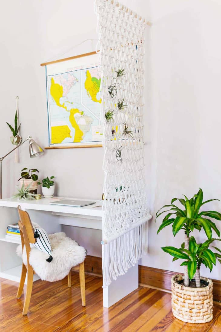 Office space with a white desk next to a hanging macrame room divider