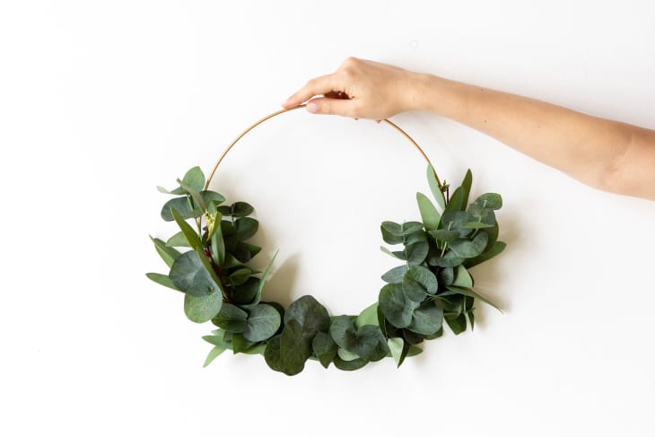 Hand holding a hoop wreath with eucalyptus branches