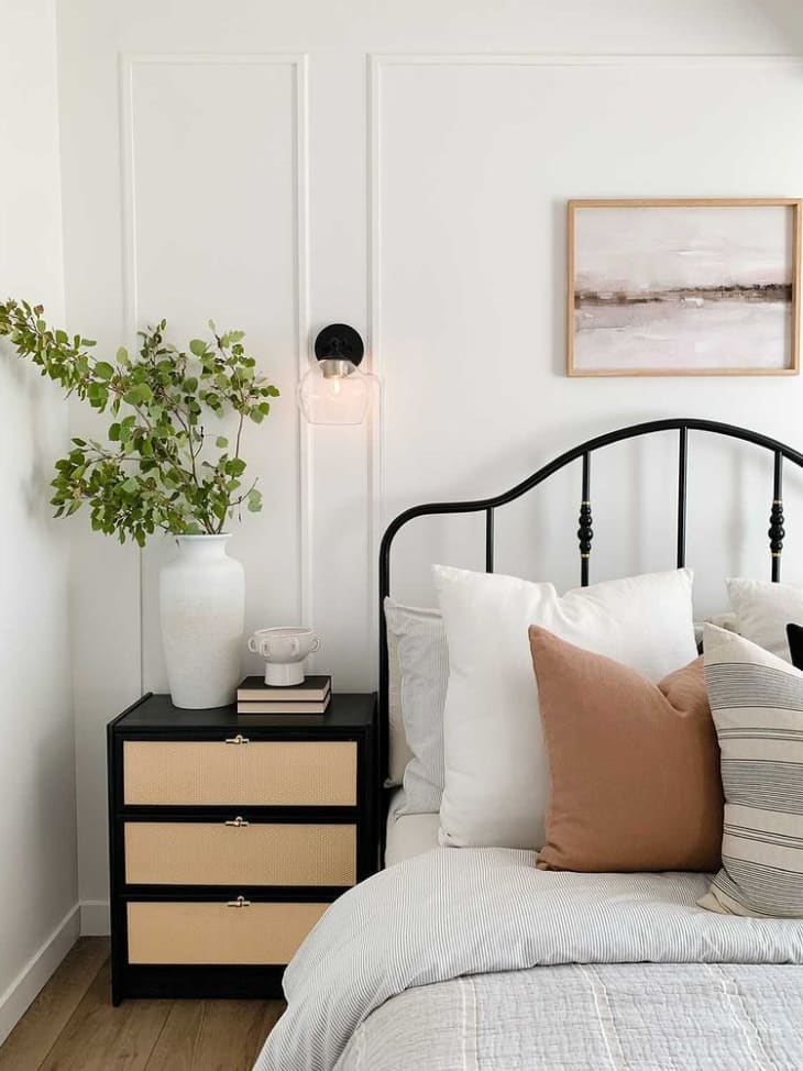 iron bed frame next to a black nightstand with caned drawers made from the IKEA RAST nightstand