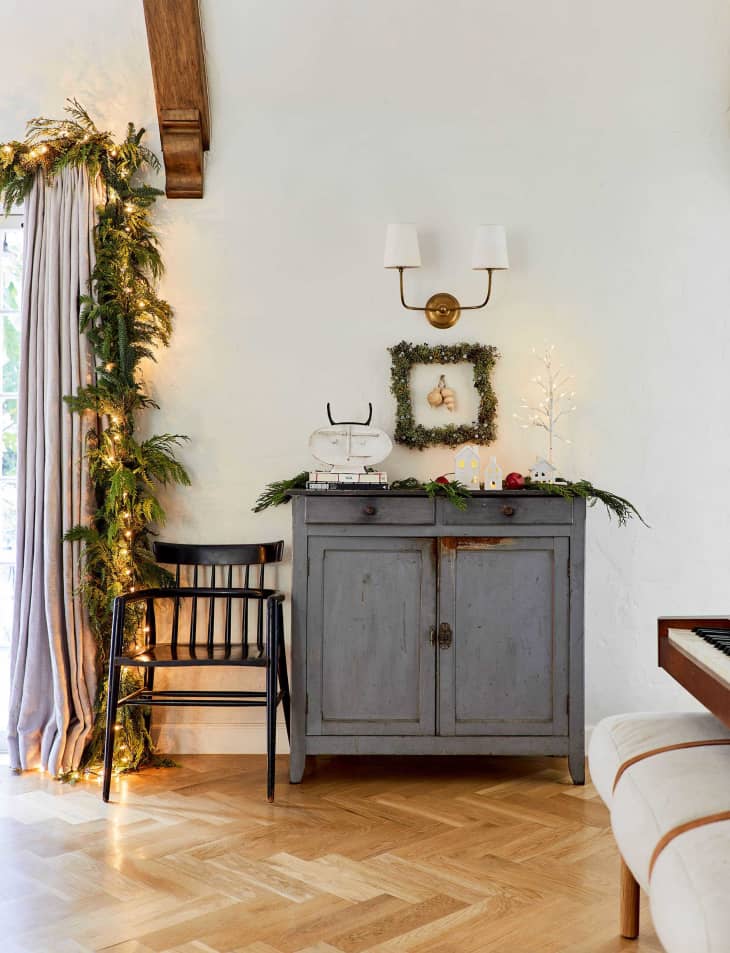 console table with square wreath framing a pair of ornaments on the wall above it