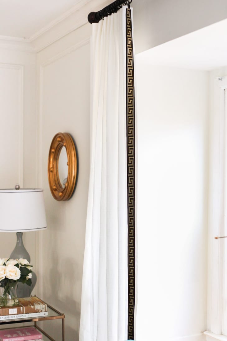 White curtain with black Greek key-patterned trim hung in window