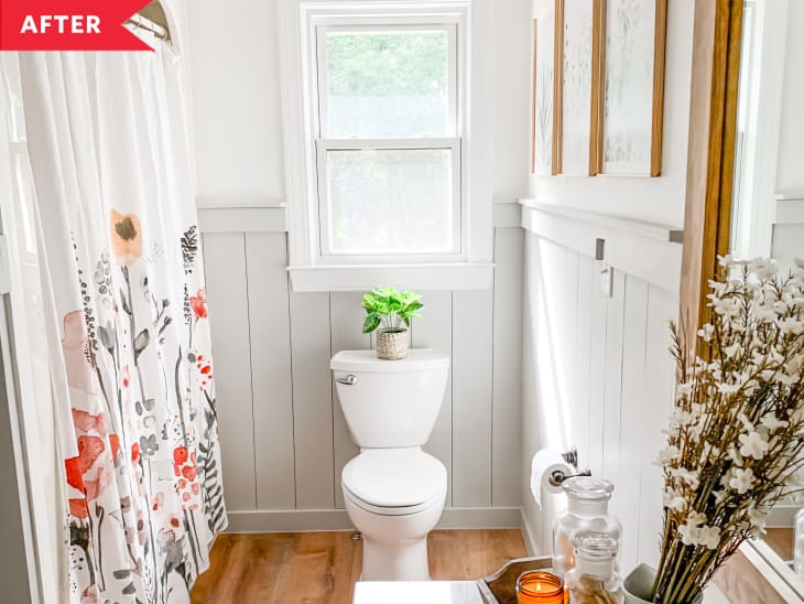 After: Toilet beneath window in bathroom with floral shower curtain