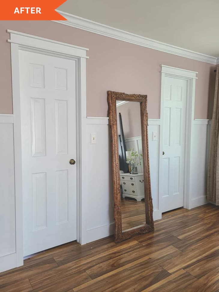 After: Bedroom with pink walls and white wainscoting, showing a floor mirror with a natural wood frame leaned up against the wall