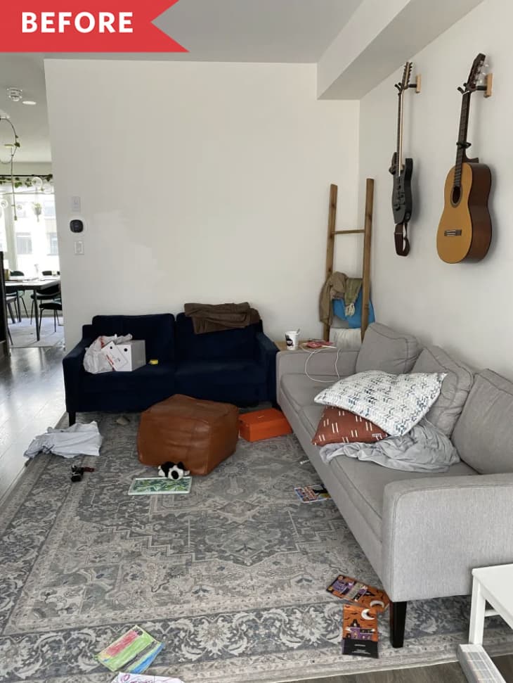 messy living room white walls grey sofa dark grey rug