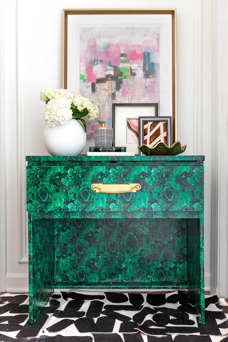 An emerald dresser with flowers and art on top