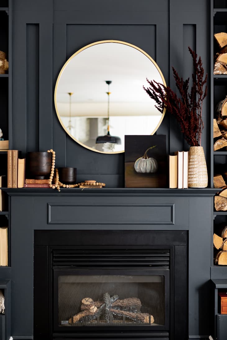 Black mantel with a round mirror hanging above