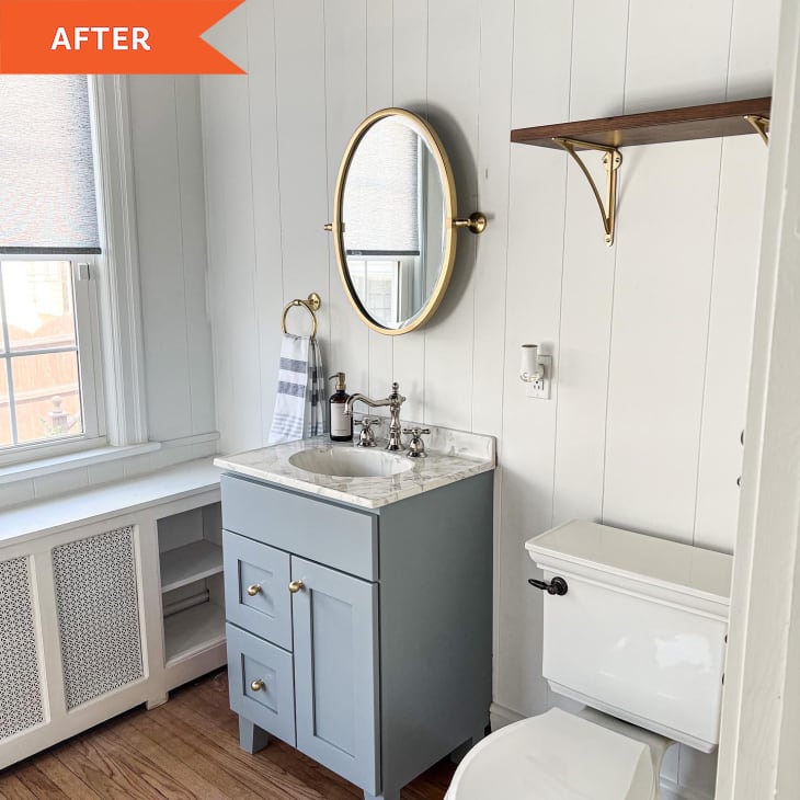 After: the side wall of a bathroom with a golden round mirror above a gray sink next to the toilet
