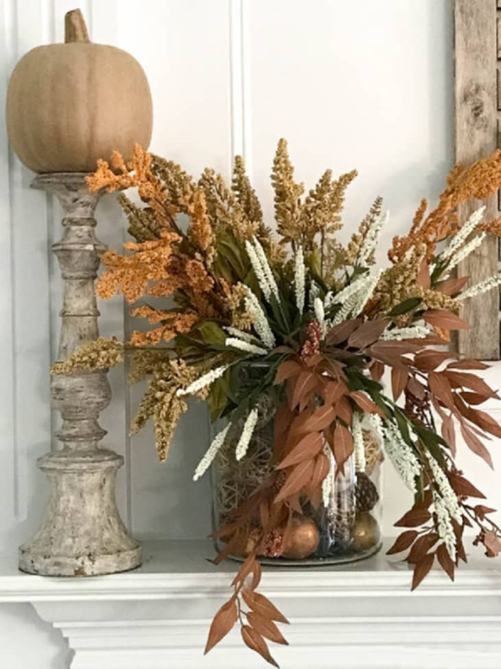 A white mantel with a large dried flower arrangement