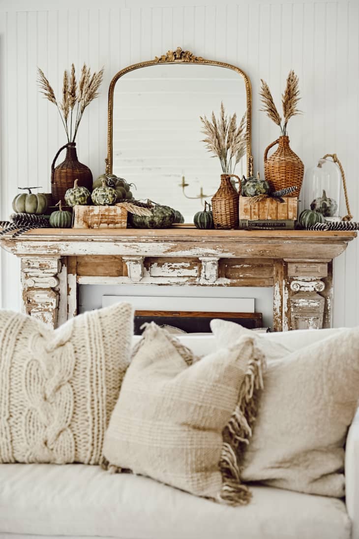 A white mantel with a mirror and dried flowers on top