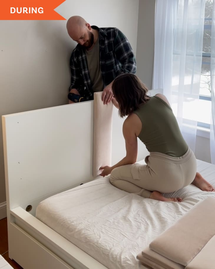 Couple working to install DIY bed headboard. Attaching one fabric-covered slat