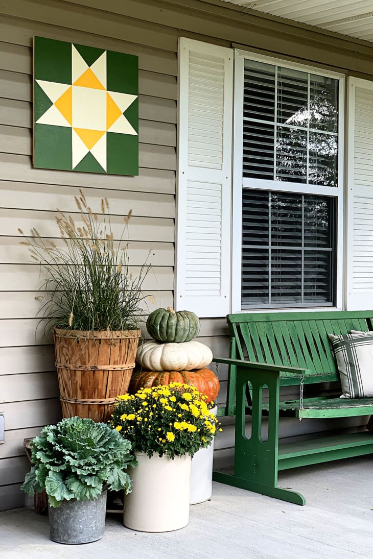 A porch with a green bench and potted plants