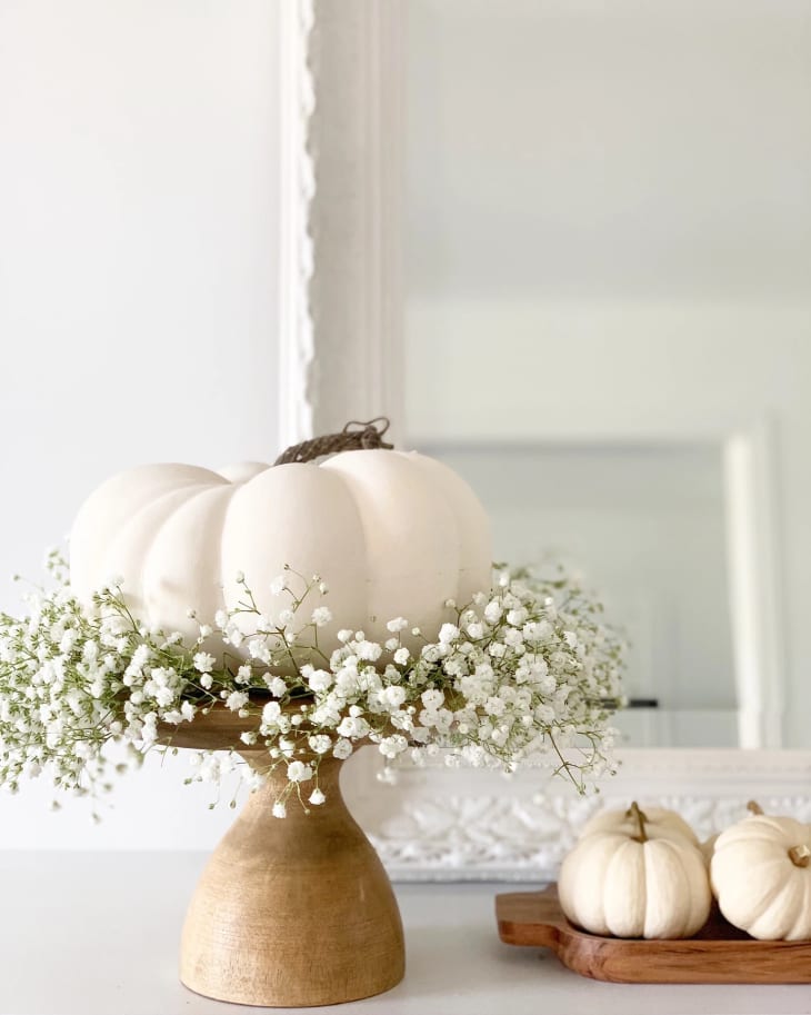 A white pumpkin on a cake plate with flowers
