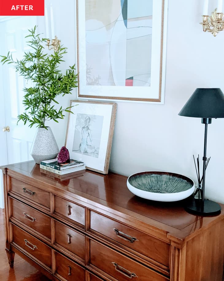 After: a wooden table with plants, lamps, and art on top