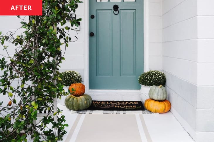 After: the entryway to the front door with stacked pumpkins and a brown welcome mat