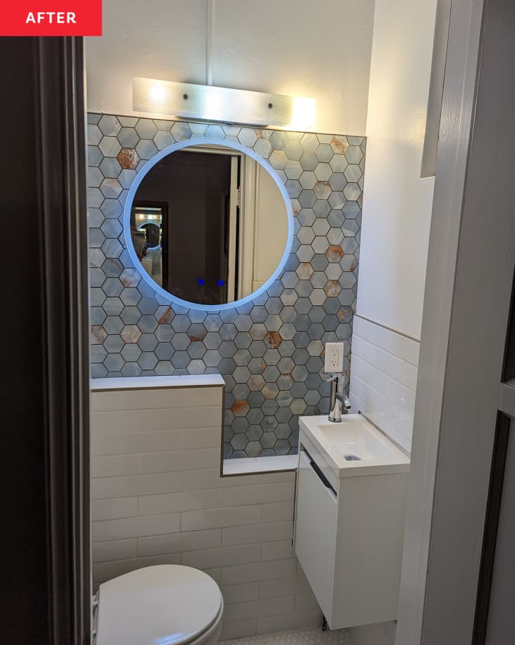 After: a bathroom with a round mirror on a light blue tiled wall