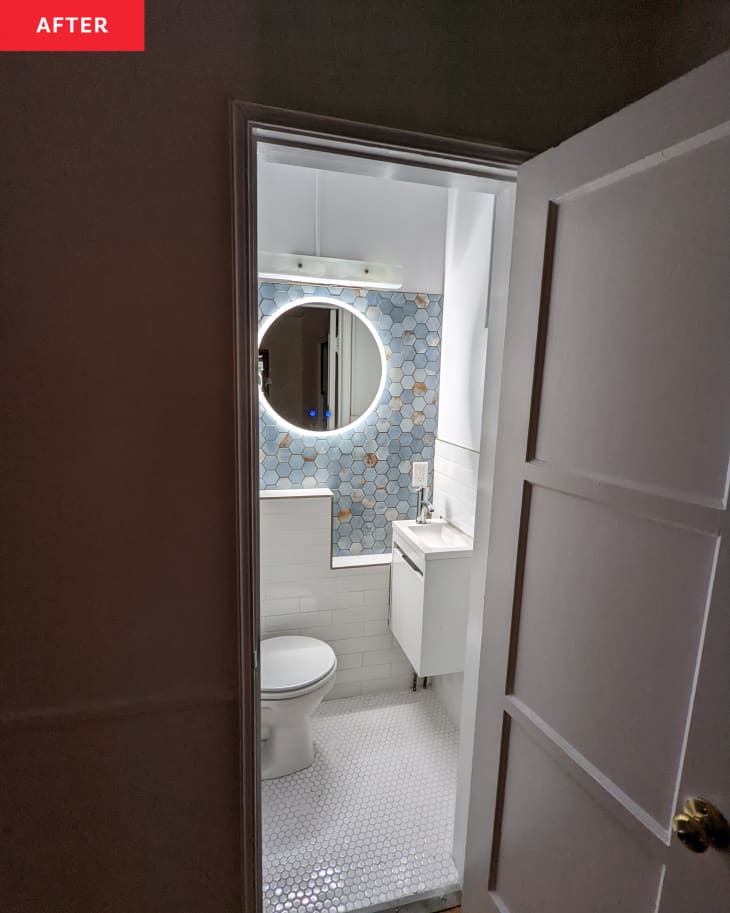 After: a door opening to reveal a bathroom with an illuminated round mirror on a light blue wall