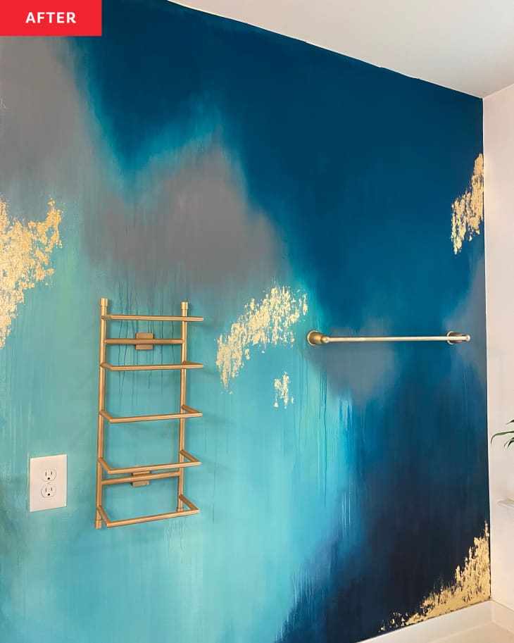 After: A bathroom wall with a blue and gold mural and gold towel bars on the wall