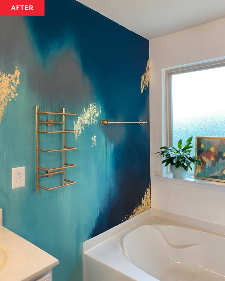 After: a blue and gold bathroom wall with a gold towel bar next to a white tub