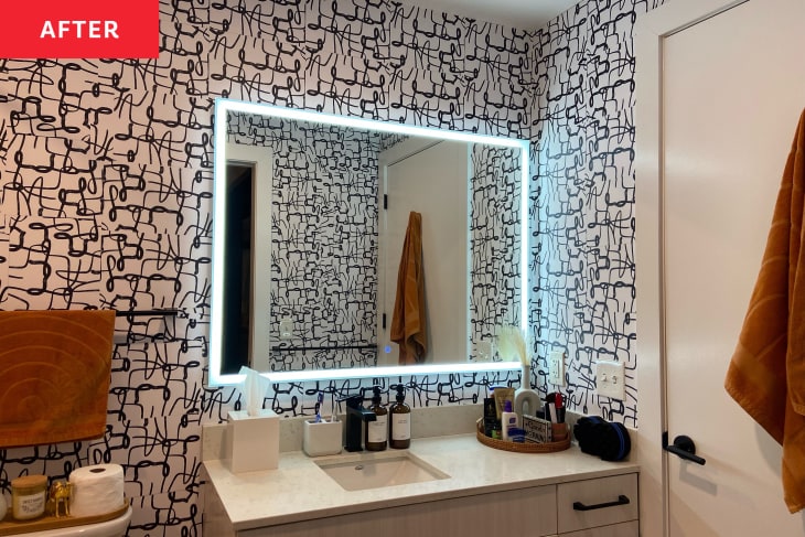 After: A rectangular mirror with a neon light on the perimeter over a bathroom sink with black and white wallpaper on the wall
