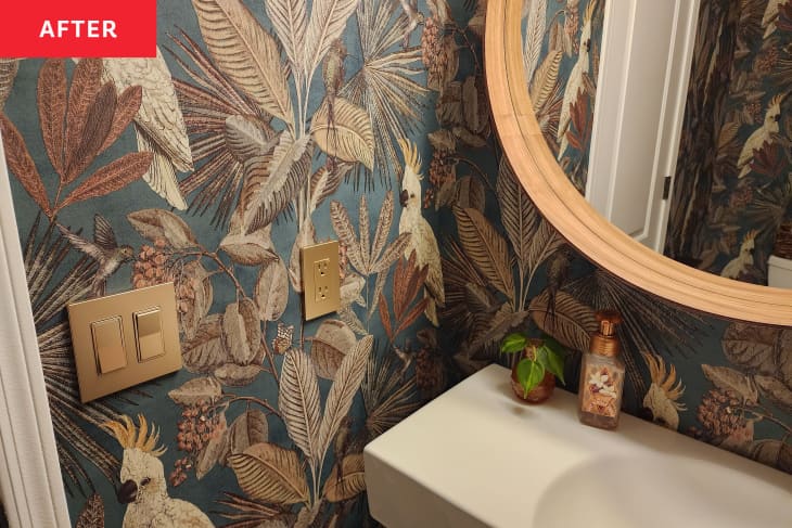 After: a bathroom with tropical bird and leaf wallpaper and tan and gold accent colors